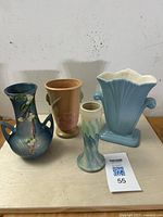 Group of four vintage American art pottery vases shown on a table including Roseville Snowberry, Weller Dogwood, red wing tulip and Peters & Reed Landsun.