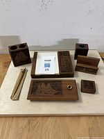 Full view of the 6-piece walnut desk set with engraved sailing ships and included pen, arranged on table.