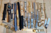 Top-down view of all 25 assorted watch straps arranged on wooden surface
