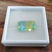 Front view of bi-colour rectangular gemstone showing blue and yellow color zones on white display box.