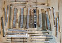 Top-down view of 34 vintage stretchy watch bracelets laid out flat on wooden surface, showing variety of metal tones and styles.