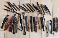 Photo showing 36 vintage ladies watch straps laid out on a wooden surface, showcasing variety of colors and sizes.