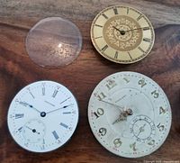 Three pocket watch movements with individual faces, two clear watch crystals, and a winding crown with stem.