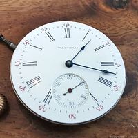 Front dial of Waltham pocket watch movement showing the white face with Roman numerals and minute marks, and subdial for seconds.
