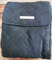 Front view of folded black quilted carrying case for headphones on wooden surface.