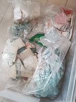 Bulk view of many small packets of watch crystals in original packaging in plastic bags.