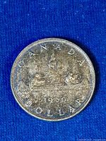 Top side of 1960 Canadian silver dollar coin showing Voyageur design with figures in canoe, date 1960, and CANADA DOLLAR inscription.