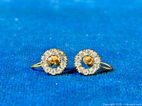 Close-up front view of the antique 9k gold circular screw-back earrings showing the arrangement of paste stones around a gold center on a blue background.