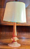 Full front view of the cranberry glass lamp with off-white lampshade, showing the overall design and condition.