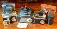 Overview of camera body on original DX-3 box, leather camera case, boxed accessories and lens pouch