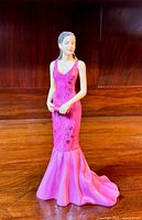Front view of the Royal Doulton Pretty Ladies Carmen figurine in pink dress on a wooden surface with warm lighting.