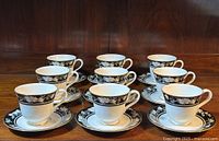 Nine Royal Doulton fine bone china tea cups and saucers arranged on a wooden surface, showing full set and pattern details.