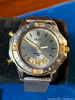 Front view of vintage Seiko Sports 100 chronograph watch showing analog dial with gold-tone markers and digital display at 6 o'clock.