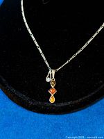 Close-up photo of the two pendants hanging on the Figaro chain showing the cubic zirconia and tri-colour amber stones.