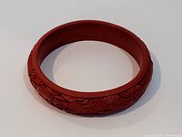 View of antique Asian red carved bangle bracelet showing floral carving and round shape