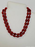Full view of two-strand red beaded necklace displayed on bust stand, showing overall design and length.