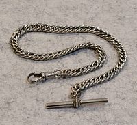 Full view of the silver curb link pocket watch chain laid out to display T-bar and swivel clasp