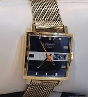 Front view of the square-faced vintage Esperanto wristwatch showing black dial with white stripe, orange second hand and date window.