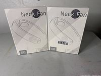 Two sealed white boxes of S8 units of bladeless neck fans shown from the front with sketches and product name visible.