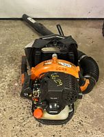 Front view showing engine housing, model number PB-265L and white fuel tank with orange cap