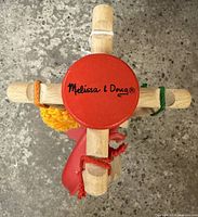 Top view showing the Melissa & Doug logo on the red circular wooden top support with four wooden arms extending.
