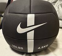 Close-up view of black Nike medicine ball showing logo, weight in pounds and kilograms, and white vertical stripe.