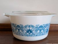 Front view of the round white Pyrex casserole dish with blue Horizon pattern and glass lid on top.