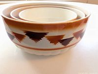 Set of three nested antique German ceramic bowls with white interiors and brown geometric exterior pattern