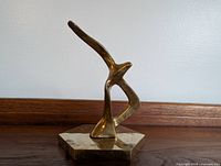 Side view of stylized brass seagull sculpture mounted on hexagonal base