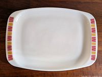 Top-down view of white rectangular milk glass platter with colorful red and yellow stripe decoration