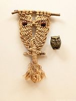 Macrame owl wall hanging displayed beside a brass owl figurine on a white background showing overall details and size comparison.