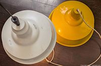 Top view of white and yellow metal hanging lamps showing shape, color and cord details
