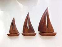 Three mid-century wooden sailboats in small, medium, large sizes against white background.