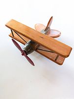 Top-angle view of the wooden toy biplane showing the upper wing, tail, and propeller.
