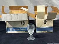 Two original Waterford Crystal boxes (one labeled 'White Wine 6 pieces') with a single white wine glass displayed between them.