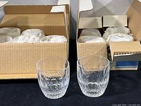 Two opened cardboard boxes each containing six wrapped tumblers with two unwrapped tumblers displayed in front