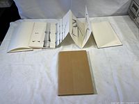 Folded travel book closed with protective sleeve beside it on white fabric background.