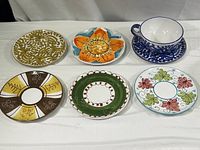 All six hand painted Italian ceramic items including five plates and one cup with saucer shown.