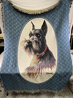 Front view of the James Hillen woven blanket featuring the black Schnauzer portrait and checkered blue border with fringe edges.