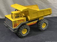 Front and side view showing overall structure, yellow metal dump bed and plastic cab, large rubber tires with Tonka branding.