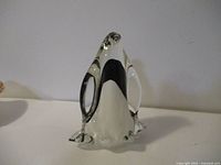 Front view of the art glass penguin showing clear glass body with black inlays.