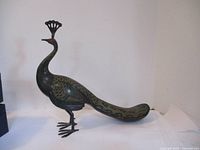 Full side view of the dark brass peacock figurine showing overall shape and size.