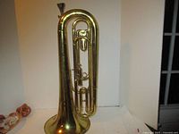 Front view of brass baritone horn showing valves and flared bell.