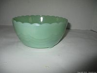 Side view showing the scalloped rim and wave pattern design on the green jadeite glass bowl