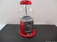 Front view of 12 inch red gumball machine with clear glass globe and metal coin mechanism.