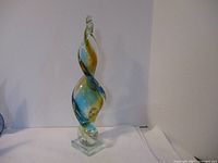 Front view of twisted glass sculpture showing amber and blue colors and clear base