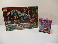 Two LEGO boxes displayed including BrickHeadz Fortnite Brite Bomber and a blue dragon set.