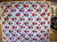 Full view of large handmade quilt hanging, showing overall pattern and size.