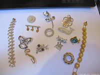 Full view of all jewelry items laid out, includes bracelets, brooches, pins, and dolphin figurine