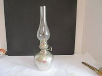 Full view of the vintage pewter oil lamp showing the rounded hammered base and clear glass chimney.